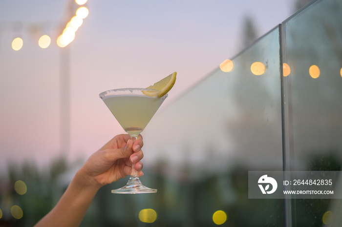 Close up human hand holding a glass of alcohol beverage in restaurant