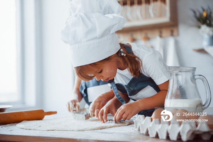 专注于烹饪。穿着白色厨师制服的家庭孩子在厨房里准备食物