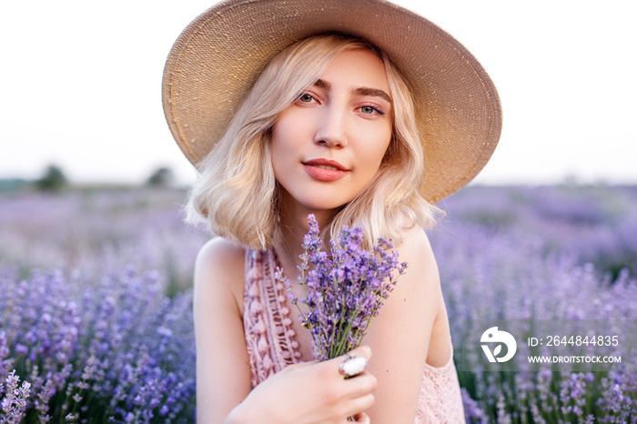 Glad woman with bouquet of lavenders in field