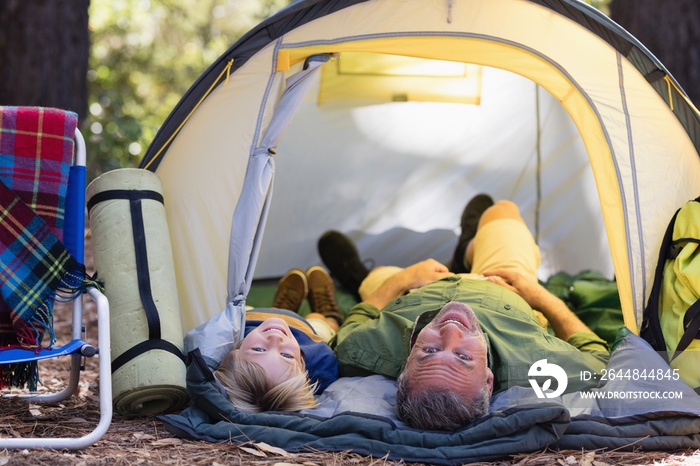 微笑的父子躺在露营地的帐篷里