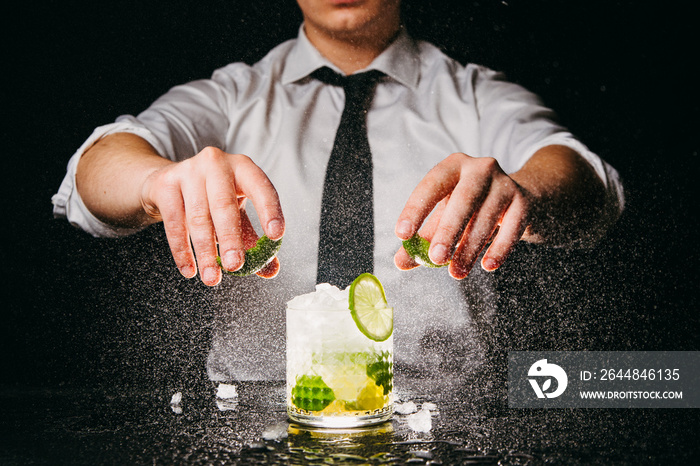 Professional bartender squeezing lime making Caipirinha cocktail