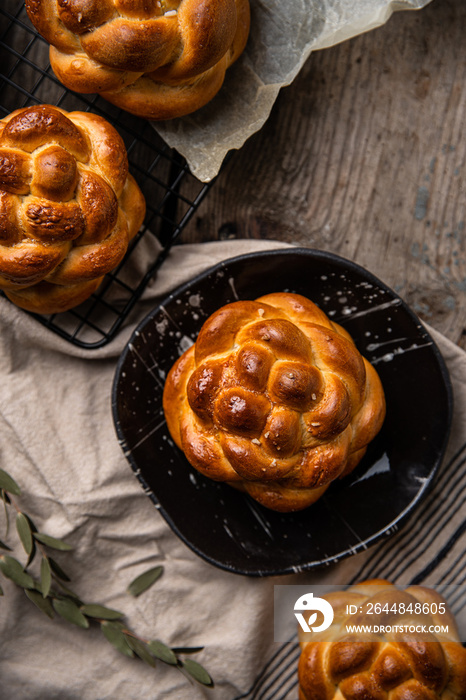 Homemade brioche knot buns on black plateon wooden table.