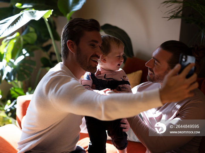 Gay couple taking�selfie�with baby daughter in living room