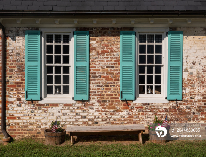弗吉尼亚州殖民地时期的房子里，白色窗户周围的简单蓝色百叶窗靠着砖墙