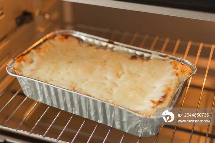 Cheese lasagna in a baking tray in the oven close-up. Process of baking lasagna. Cooking Italian foo