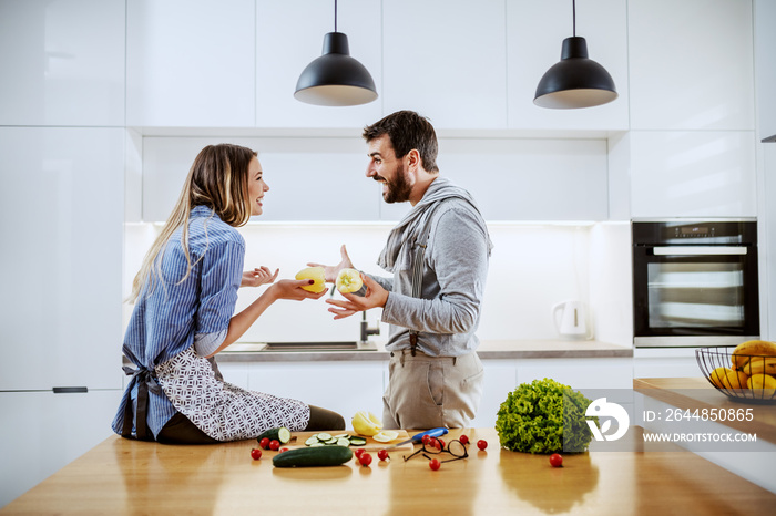 Young attractive caucasian couple holding peppers and talking about healthy lifestyle. Woman sitting