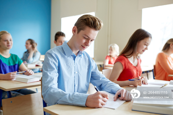 group of students with books writing school test