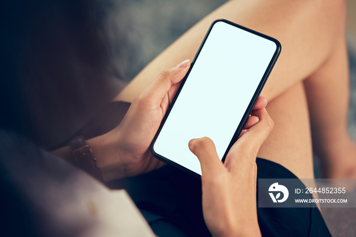 Woman holding smartphone blank screen on the sofa in house. Take your screen to put on advertising.