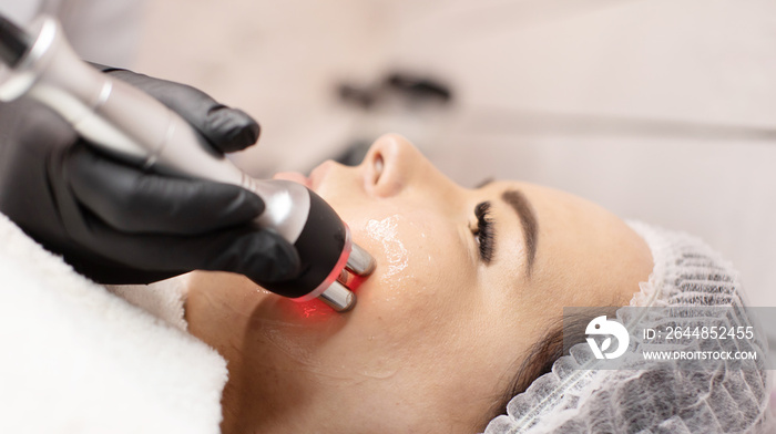 Hardware cosmetology. Closeup picture of happy young woman getting rf lifting procedure in a beauty 