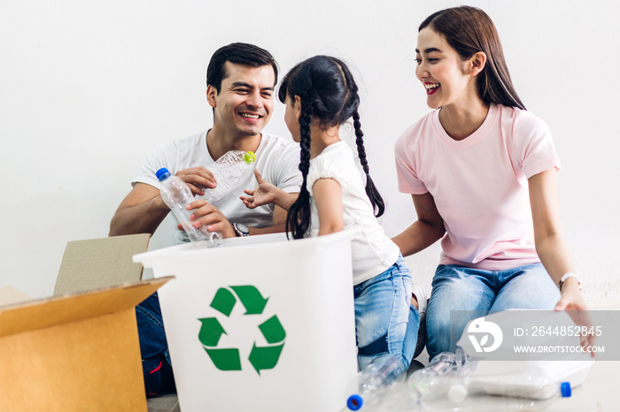 Happy smiling family having fun putting empty recycling plastic bottles and paper into the recycle b