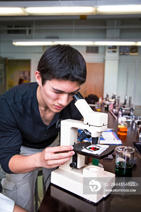 Young man looking through microscope