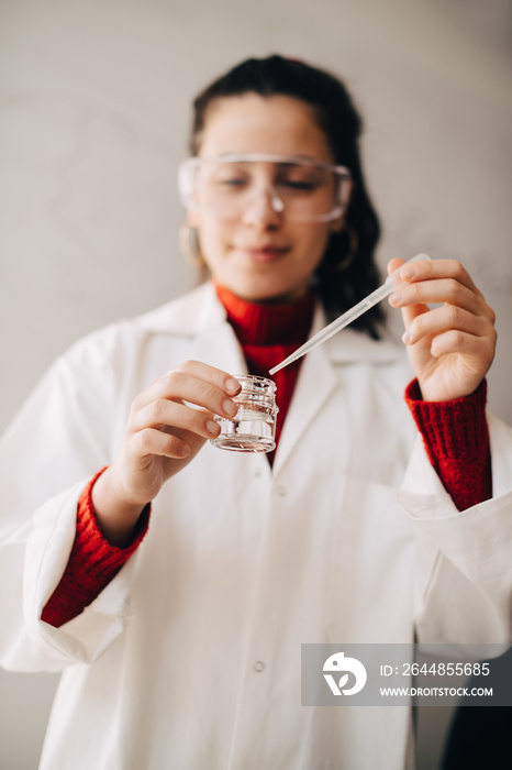 Female university student in lab coat experimenting during chemistry class