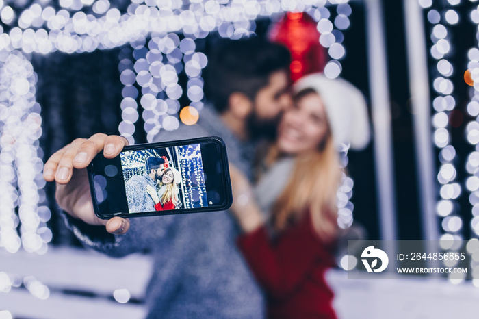 Beautiful young romantic couple taking selfie photo during ice skating.