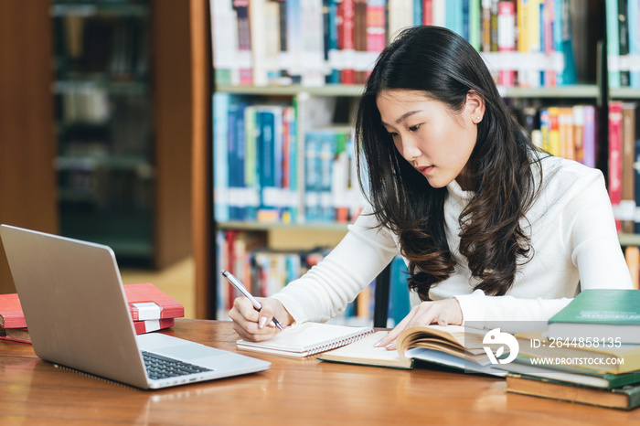 Young beautiful asian student study in the school library and using laptop for online learning.e-Lea