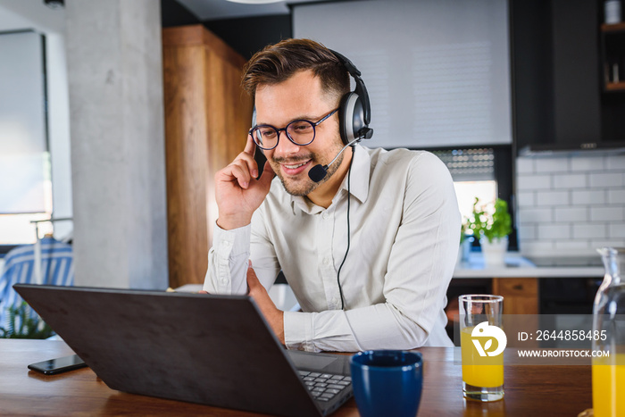 Young handsome man working from home, sitting in front of laptop computer having meeting over intern