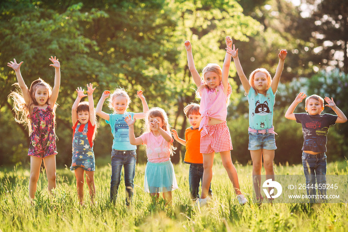 Group of friends running happily together in the grass and jumping.