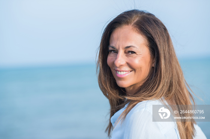 Beautiful middle age hispanic woman standing with smile on face at the ocean. Smiling confident and 