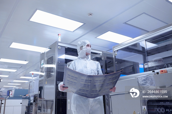 Female worker holding flex circuit in flexible electronics factory clean room