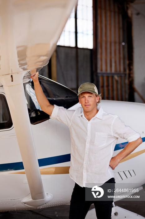 Portrait of confident man standing by airplane