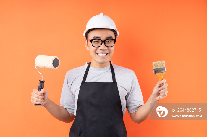 Asian painter holding paint brush posing on orange background