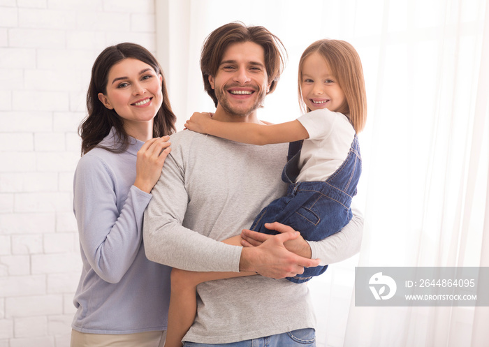 Happy Father And Mother Posing With Their Little Daughter On Hands