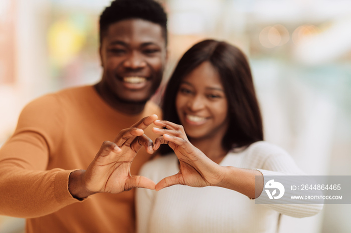 Happy smiling black couple making heart shape with hands