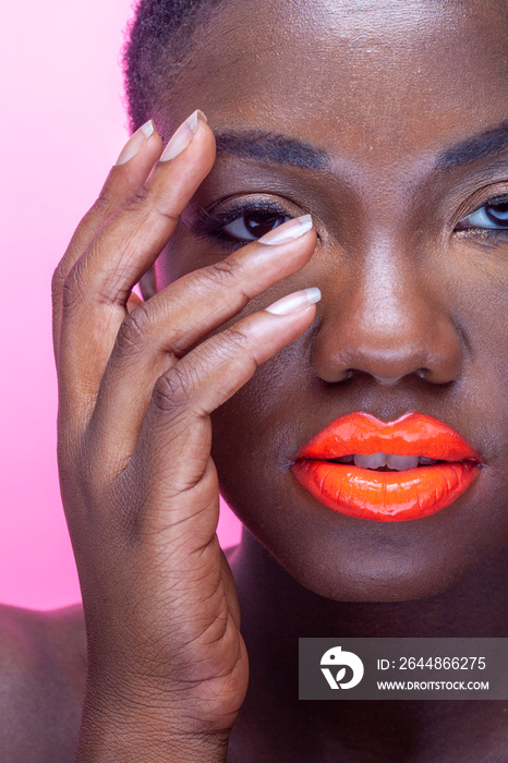 Studio portrait of woman with orange lips against pink background