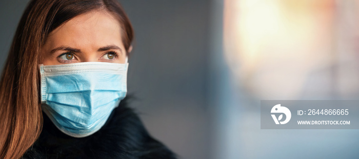 Young woman wearing disposable blue virus face mouth nose mask, closeup portrait, banner with space 