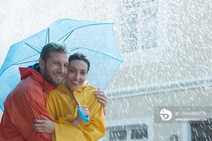 Portrait happy couple with umbrella in rain