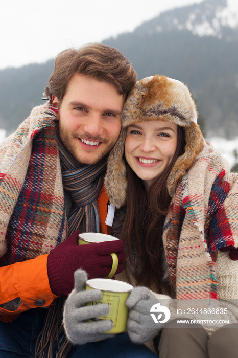 Portrait happy young couple in warm clothing drinking coffee