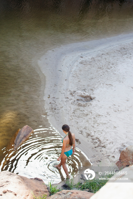 Young woman in bikini stepping into lake