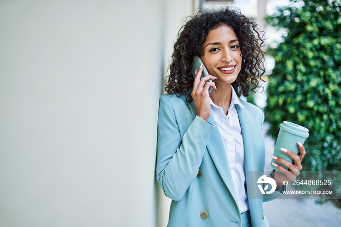 Young hispanic business woman wearing professional look smiling confident at the city speaking on th