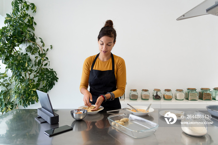 一位身材矮小的女士在烹饪课上用厨房里的一些家常菜食谱直播