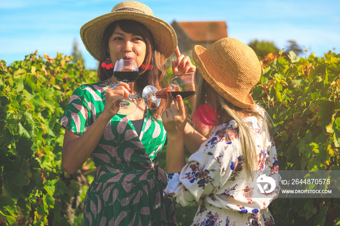 Happy asian woman drinking red wine with friend at vinyard during vacation,  celebration concep
