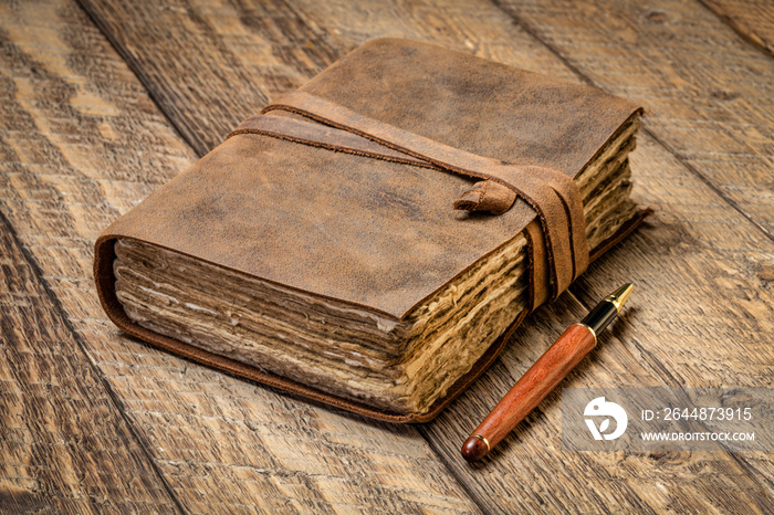 antique leatherbound journal with decked edge handmade paper pages and a stylish pen on a rustic woo