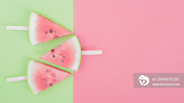 watermelon slice on green and pink background with stick