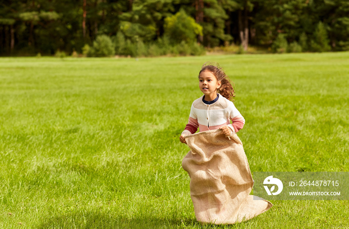 童年、休闲和人的概念——快乐的小女孩在公园玩跳袋游戏