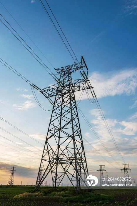 silhouette of high voltage power lines against a colorful sky at sunrise.