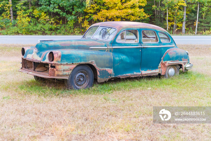 Abandoned old car decaying in the middle of a meadow