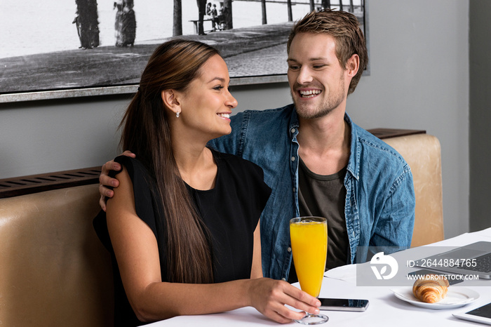 Young couple sitting in cafe with technology on table