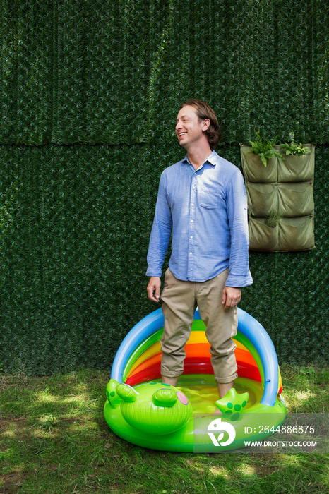 Man standing in inflatable pool in backyard