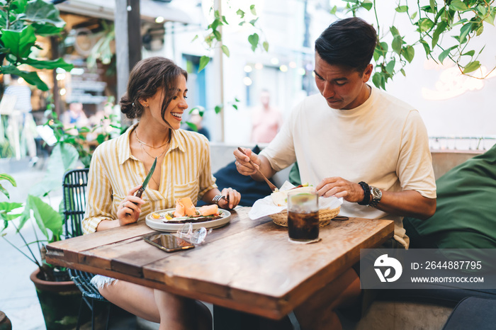 满足年轻夫妇在户外咖啡馆享用午餐