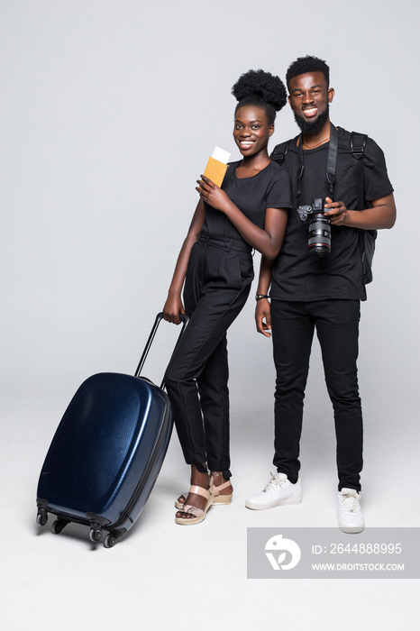 Full length portrait of a young african couple walking with suitcases for travel isolated over white
