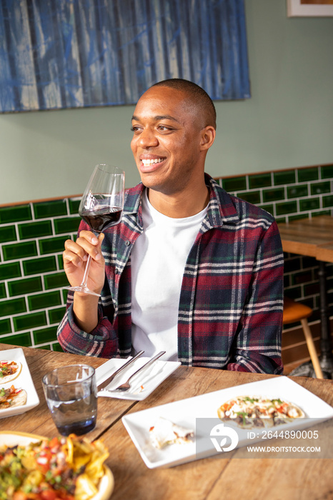 英国，伦敦，微笑的男人在餐厅餐桌上享用红酒
