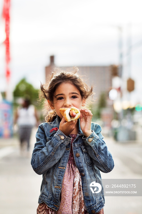 Girl (6-7) eating hot dog