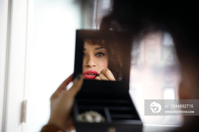 Young woman applying red lipstick