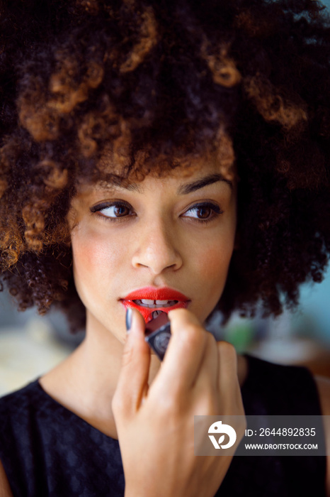 Young woman applying red lipstick