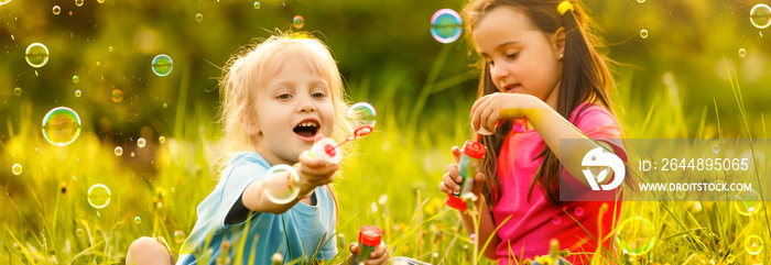 Little girls blowing soap bubbles with her grandmother outdoors