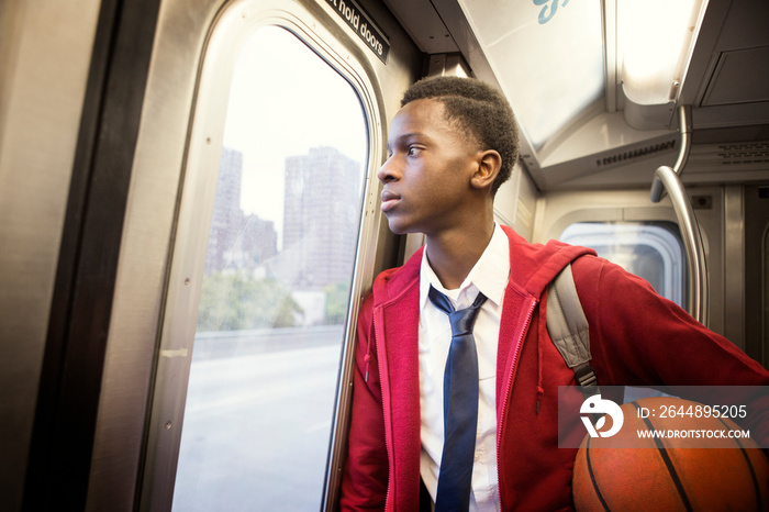 Teenage boy (14-15) in train with basketball