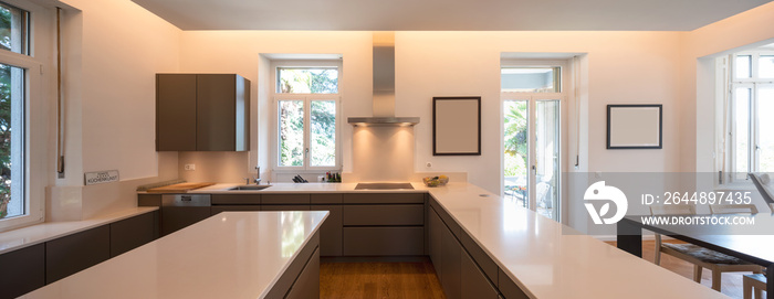 Modern kitchen in a period villa with window and parquet. White counters and brown doors